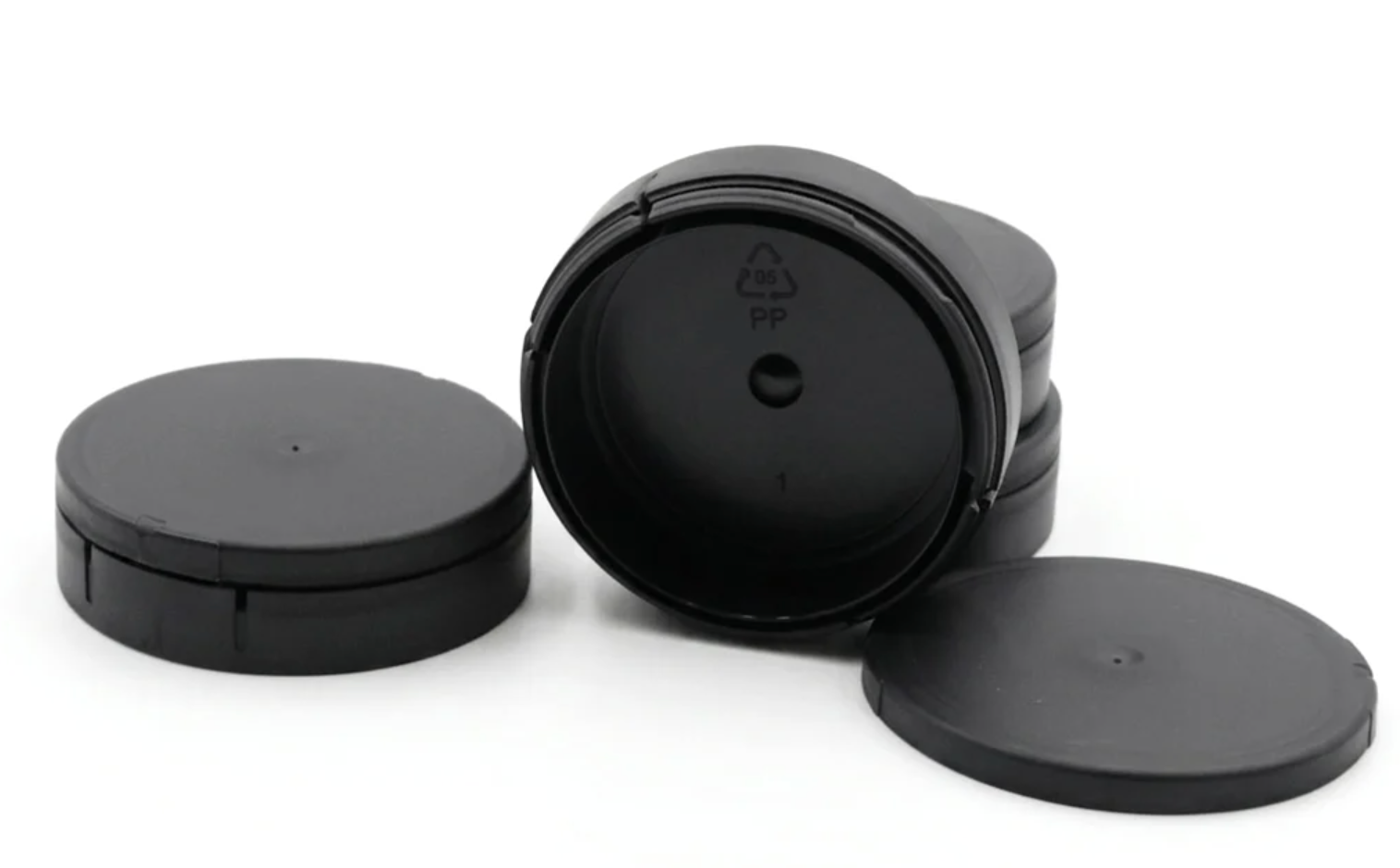 Stacked black empty plastic snus cans with lids showing PP food-grade material marking